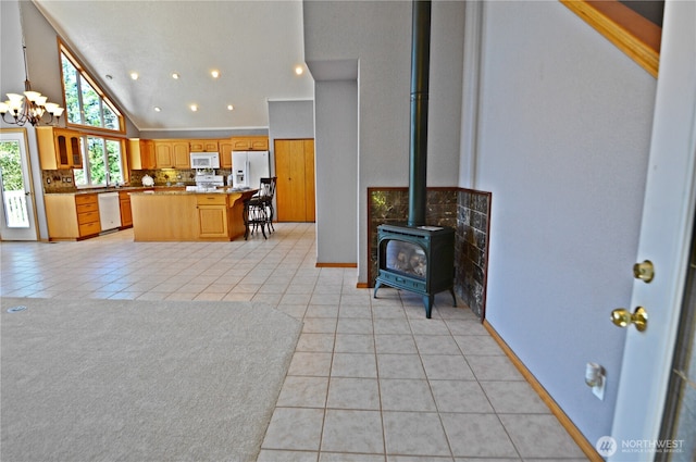 1923 SE Maple Dr, Chehalis, WA 98532 - kitchen with white appliances, light tile patterned floors, a chandelier, a wood stove, and high vaulted ceiling