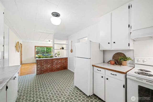 3032 Tulip Rd, Bellingham, WA 98225 - kitchen featuring white appliances, tile patterned floors, white cabinetry, brick wall, and premium range hood