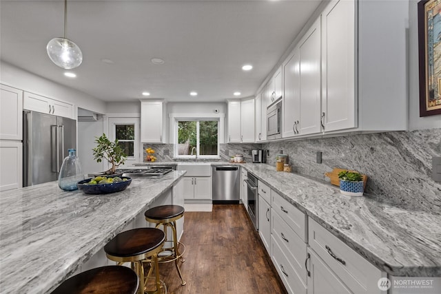 8213 S Fawcett Ave, Tacoma, WA 98408 - kitchen with stainless steel appliances, a breakfast bar, dark wood-style floors, white cabinetry, and recessed lighting
