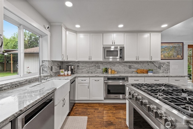 8213 S Fawcett Ave, Tacoma, WA 98408 - kitchen with appliances with stainless steel finishes, light stone countertops, white cabinets, backsplash, and recessed lighting
