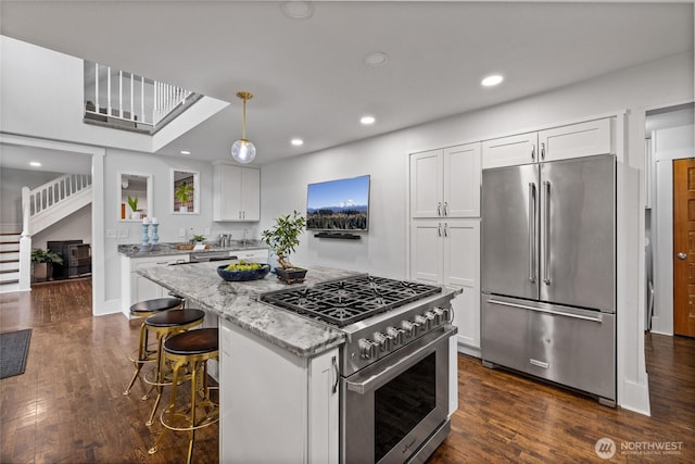 8213 S Fawcett Ave, Tacoma, WA 98408 - kitchen with high quality appliances, white cabinetry, light stone countertops, a kitchen island, and recessed lighting