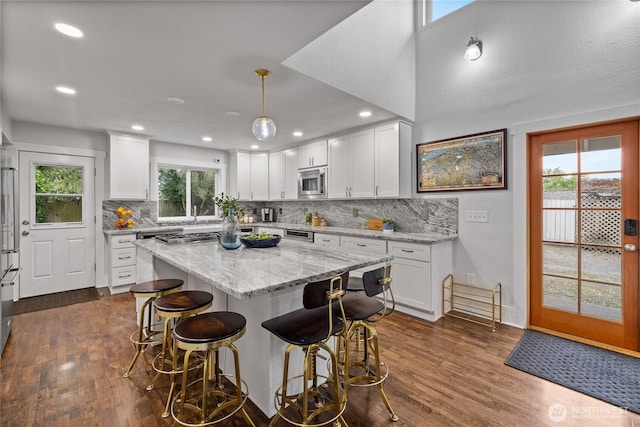 8213 S Fawcett Ave, Tacoma, WA 98408 - kitchen featuring stainless steel microwave, decorative backsplash, white cabinetry, dark wood-style flooring, and recessed lighting
