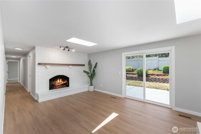 10218 63rd Avenue Ct E, Puyallup, WA 98373 - unfurnished living room featuring a skylight, a brick fireplace, wood finished floors, and track lighting