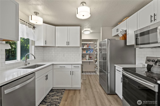 1216 NE Vena Ave, Bremerton, WA 98311 - kitchen featuring appliances with stainless steel finishes, light countertops, white cabinets, light wood-type flooring, and a textured ceiling