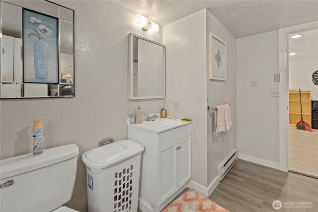 1216 NE Vena Ave, Bremerton, WA 98311 - bathroom featuring a baseboard heating unit, wood finished floors, vanity, and a textured ceiling