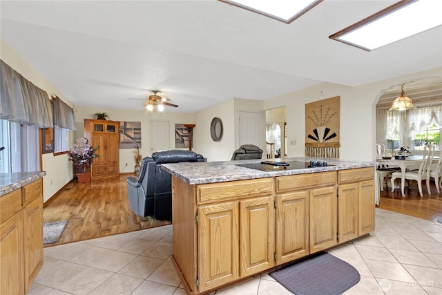 6314 75th Avenue Ct W, University Place, WA 98467 - kitchen featuring light tile patterned flooring, black electric cooktop, arched walkways, a center island, and ceiling fan