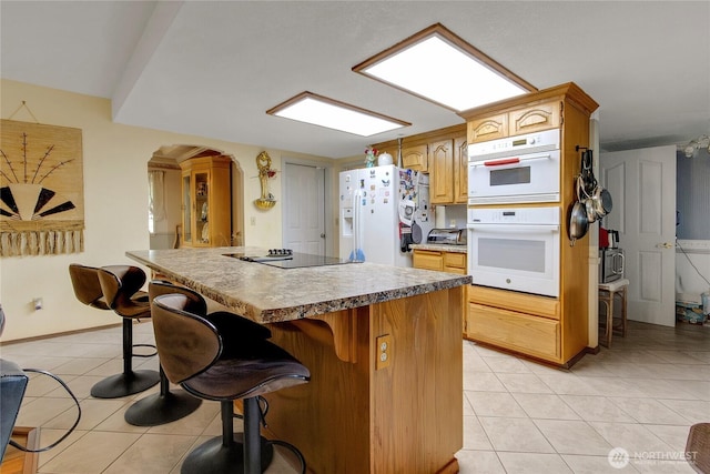 6314 75th Avenue Ct W, University Place, WA 98467 - kitchen with white appliances, light tile patterned floors, arched walkways, a center island, and a breakfast bar