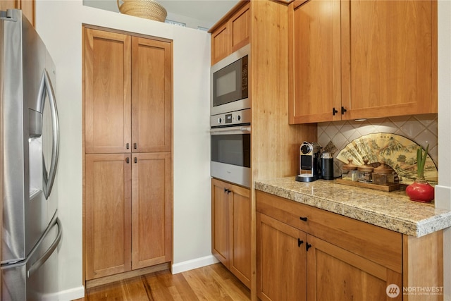 32 Heron Rd, Port Ludlow, WA 98365 - kitchen with appliances with stainless steel finishes, tasteful backsplash, light wood-type flooring, and light countertops