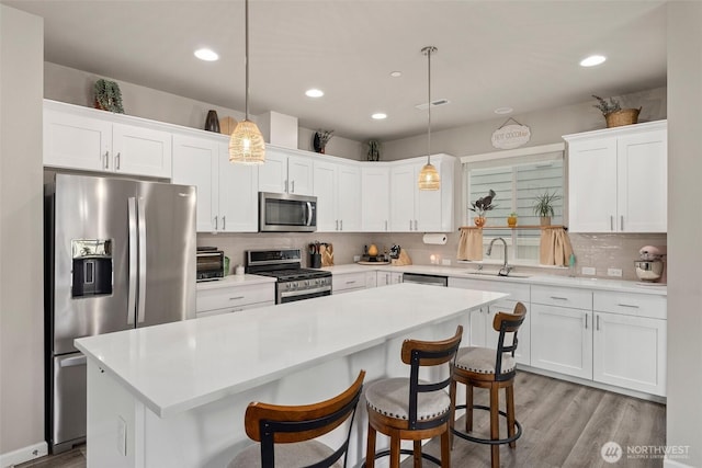 3115 Stephanie Loop NE, Lacey, WA 98516 - kitchen featuring appliances with stainless steel finishes, a center island, white cabinets, light wood finished floors, and a breakfast bar area