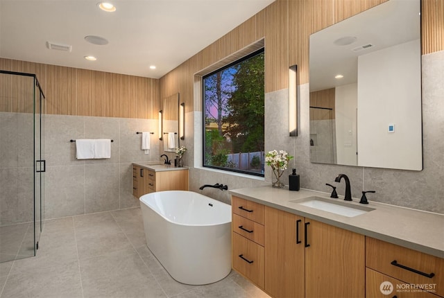 10425 NE 28th Pl, Bellevue, WA 98004 - bathroom with tile walls, two vanities, a stall shower, a freestanding tub, and tile patterned floors