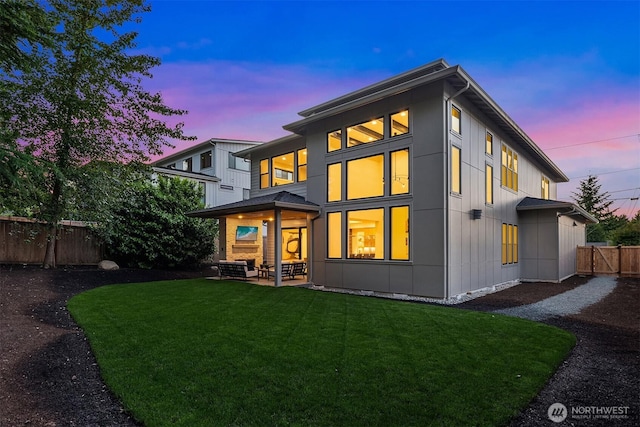 10425 NE 28th Pl, Bellevue, WA 98004 - back of property at dusk with board and batten siding, a fenced backyard, and a patio