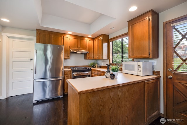 4745 35th Ave SW, Seattle, WA 98126 - kitchen featuring appliances with stainless steel finishes, under cabinet range hood, a peninsula, brown cabinets, and recessed lighting