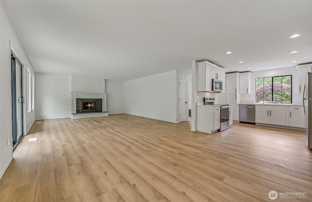 13428 SE 302nd Pl, Auburn, WA 98092 - unfurnished living room with light wood finished floors, recessed lighting, and a lit fireplace