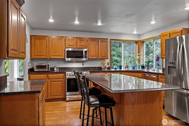6345 Agnes Rd NE, Tacoma, WA 98422 - kitchen featuring appliances with stainless steel finishes, a kitchen bar, a kitchen island, recessed lighting, and dark stone counters
