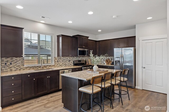 3119 13th Avenue Ct NW, Puyallup, WA 98371 - kitchen featuring appliances with stainless steel finishes, dark brown cabinets, a breakfast bar area, tasteful backsplash, and recessed lighting