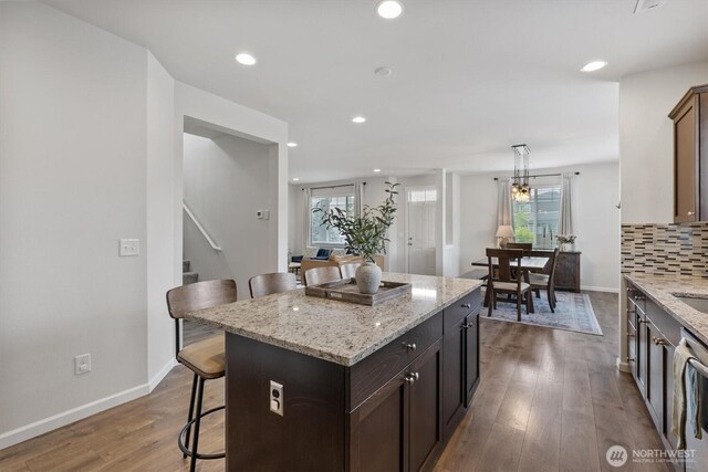 3119 13th Avenue Ct NW, Puyallup, WA 98371 - kitchen featuring a kitchen breakfast bar, a kitchen island, wood finished floors, light stone counters, and recessed lighting