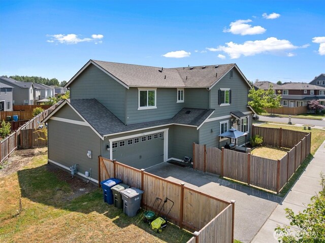 3119 13th Avenue Ct NW, Puyallup, WA 98371 - back of house with a shingled roof, driveway, a garage, a residential view, and a fenced backyard