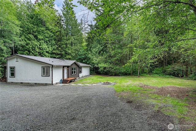 5279 SE Lars Hansen Rd, Port Orchard, WA 98367 - view of front facade featuring a fire pit, a forest view, a front yard, and driveway