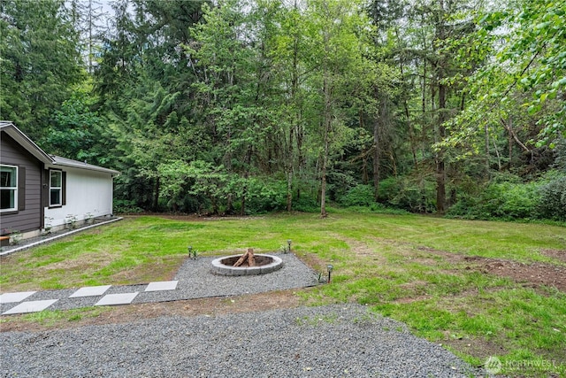 5279 SE Lars Hansen Rd, Port Orchard, WA 98367 - view of green lawn featuring a fire pit and a wooded view