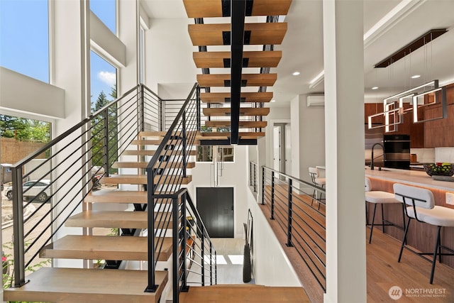 11888 SE 5th St, Bellevue, WA 98005 - staircase with a towering ceiling, wood finished floors, a wall mounted air conditioner, and recessed lighting