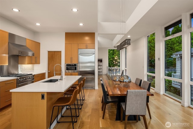 3812 Cascadia Ave S, Seattle, WA 98118 - kitchen featuring high quality appliances, wall chimney range hood, modern cabinets, recessed lighting, and light wood finished floors