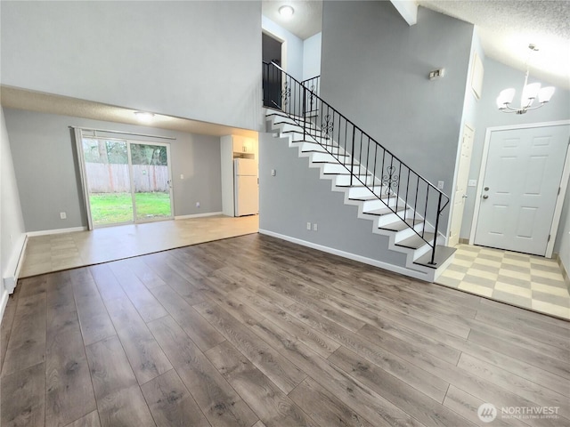 3624 159th Street Ct E, Tacoma, WA 98446 - unfurnished living room featuring high vaulted ceiling, stairs, a chandelier, and wood finished floors