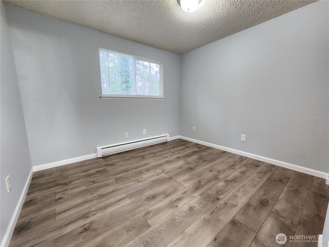3624 159th Street Ct E, Tacoma, WA 98446 - spare room featuring baseboard heating, a textured ceiling, and wood finished floors