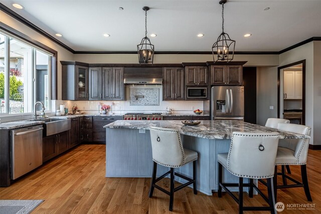 453 Spruce Ct NW, East Wenatchee, WA 98802 - kitchen featuring stainless steel appliances, ornamental molding, light stone counters, tasteful backsplash, and a center island