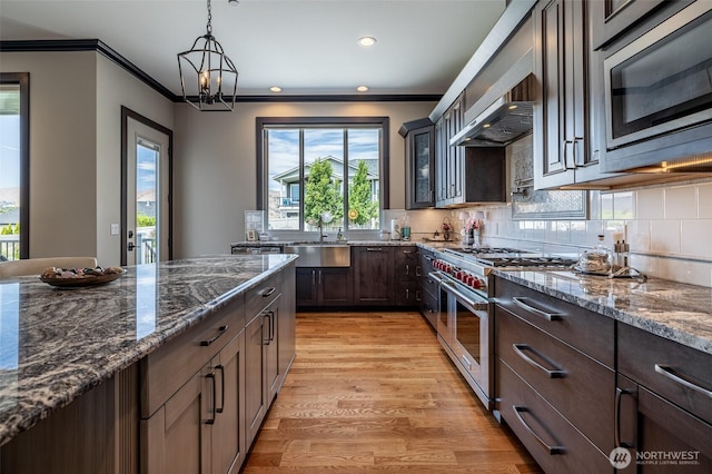 453 Spruce Ct NW, East Wenatchee, WA 98802 - kitchen with appliances with stainless steel finishes, dark stone counters, ornamental molding, glass insert cabinets, and dark brown cabinets
