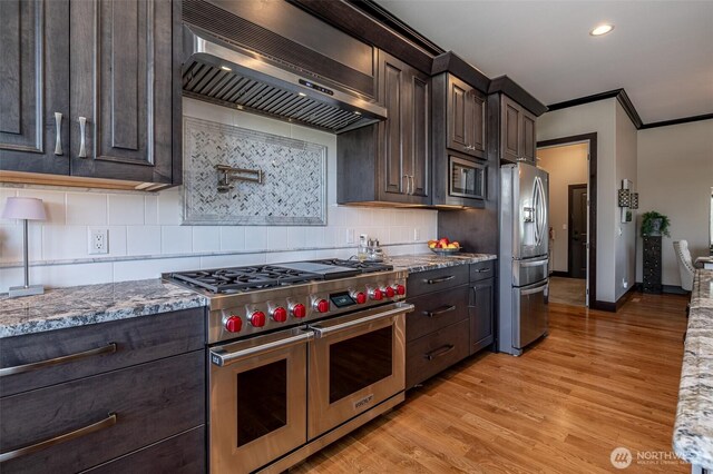 453 Spruce Ct NW, East Wenatchee, WA 98802 - kitchen featuring stainless steel appliances, extractor fan, dark brown cabinetry, light wood-type flooring, and light stone counters