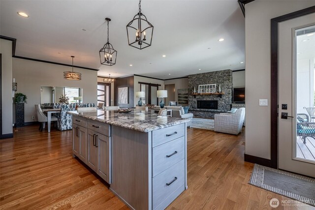 453 Spruce Ct NW, East Wenatchee, WA 98802 - kitchen featuring a chandelier, a stone fireplace, light wood finished floors, decorative light fixtures, and light stone countertops
