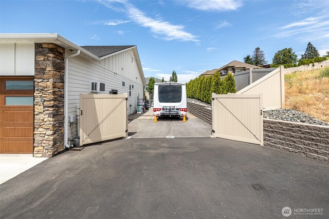 453 Spruce Ct NW, East Wenatchee, WA 98802 - view of home's exterior with a gate, stone siding, board and batten siding, and roof with shingles
