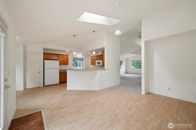 424 Wilson Ln, Sumas, WA 98295 - kitchen featuring white appliances, a skylight, open floor plan, brown cabinets, and light wood-style floors