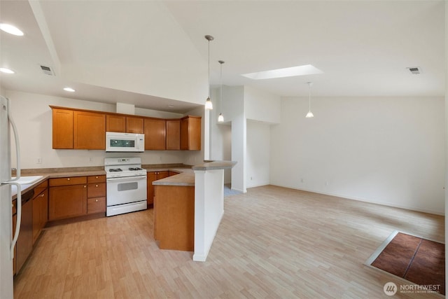 424 Wilson Ln, Sumas, WA 98295 - kitchen with white appliances, a peninsula, a skylight, brown cabinetry, and light wood-style floors