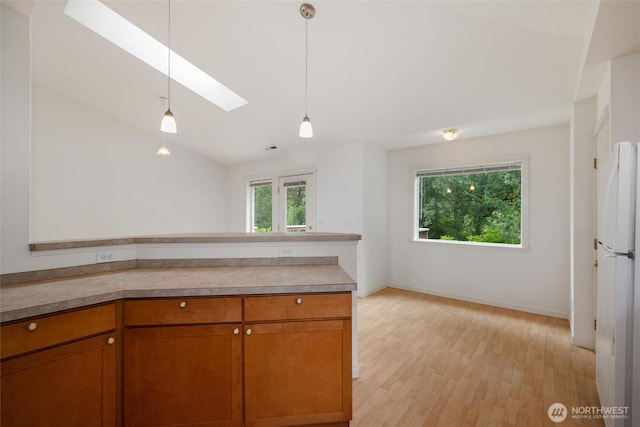 424 Wilson Ln, Sumas, WA 98295 - kitchen featuring a skylight, brown cabinetry, light wood-type flooring, decorative light fixtures, and vaulted ceiling