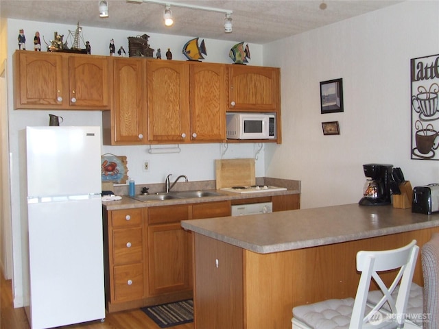 304 NW 14th St NW Unit 207, Long Beach, WA 98631 - kitchen featuring white appliances, a peninsula, a breakfast bar area, and brown cabinets