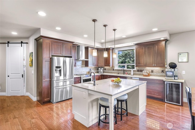 1301 Broad St, Bellingham, WA 98229 - kitchen with wine cooler, stainless steel appliances, wall chimney range hood, light countertops, and decorative backsplash
