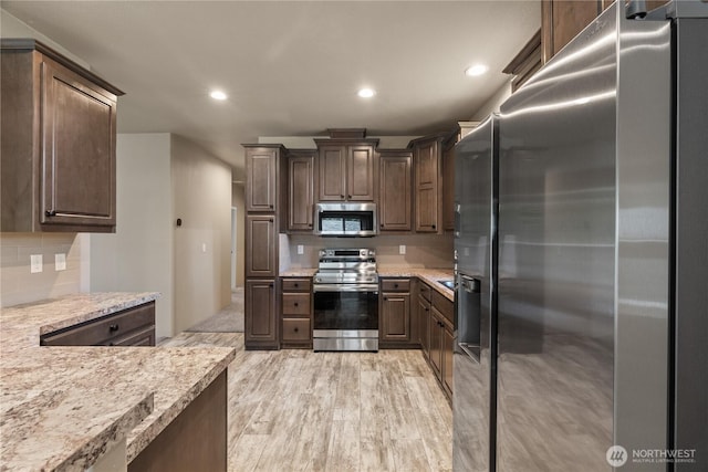 712 Syzygy Ct SE, Ocean Shores, WA 98569 - kitchen featuring appliances with stainless steel finishes, tasteful backsplash, recessed lighting, dark brown cabinets, and light wood-style floors