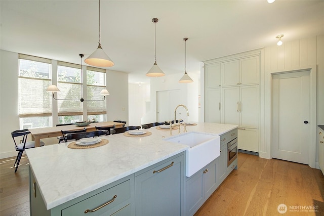 9208 11th Ave NW, Seattle, WA 98117 - kitchen featuring light wood-style floors, an island with sink, and pendant lighting