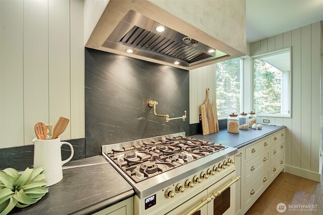 9208 11th Ave NW, Seattle, WA 98117 - kitchen featuring range with two ovens, wall chimney exhaust hood, wood finished floors, dark countertops, and recessed lighting