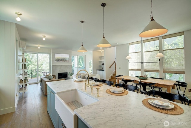 9208 11th Ave NW, Seattle, WA 98117 - kitchen with open floor plan, light wood-style floors, a fireplace, light stone counters, and pendant lighting