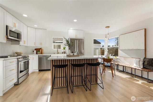 12852 Occidental Ave S, Seattle, WA 98168 - kitchen featuring stainless steel appliances, light wood-style flooring, a kitchen island, tasteful backsplash, and recessed lighting