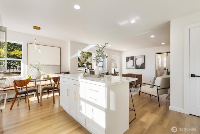 12852 Occidental Ave S, Seattle, WA 98168 - kitchen featuring white cabinets, light wood finished floors, a kitchen island, recessed lighting, and a kitchen bar