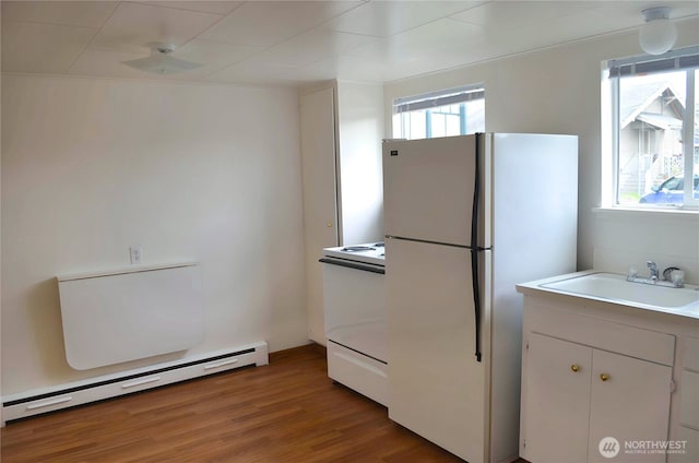 306 2nd St NE, Auburn, WA 98002 - kitchen featuring white appliances, a baseboard radiator, light wood-style flooring, light countertops, and white cabinets