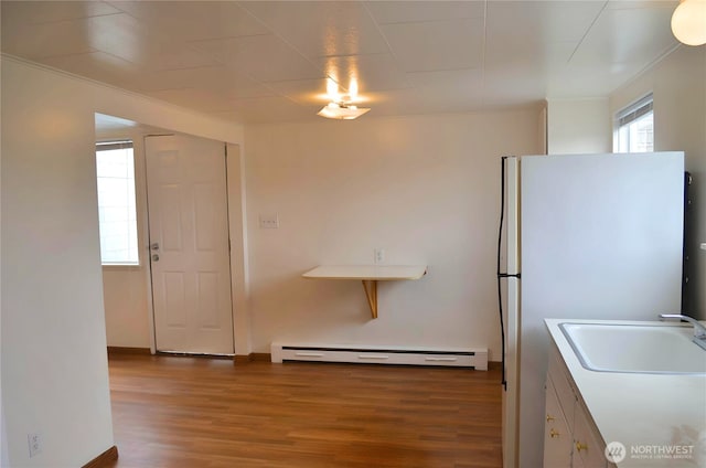 306 2nd St NE, Auburn, WA 98002 - kitchen with baseboard heating, wood finished floors, freestanding refrigerator, ornamental molding, and white cabinets