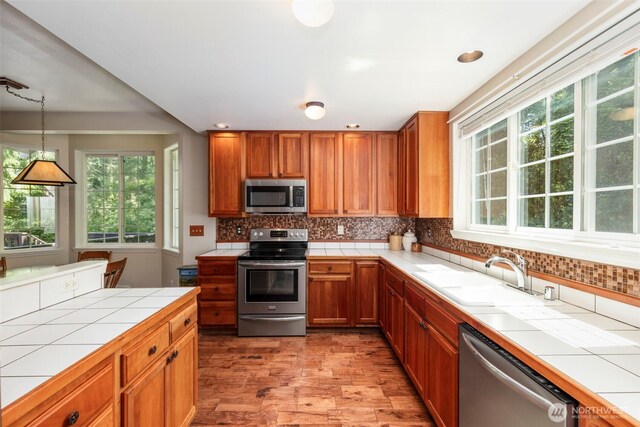 4766 Mason St, Port Townsend, WA 98368 - kitchen with appliances with stainless steel finishes, tile countertops, decorative backsplash, brown cabinetry, and recessed lighting