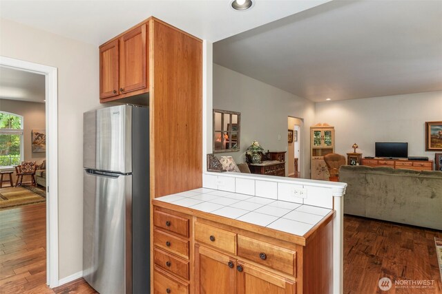 4766 Mason St, Port Townsend, WA 98368 - kitchen featuring freestanding refrigerator, tile counters, dark wood-style flooring, open floor plan, and brown cabinets