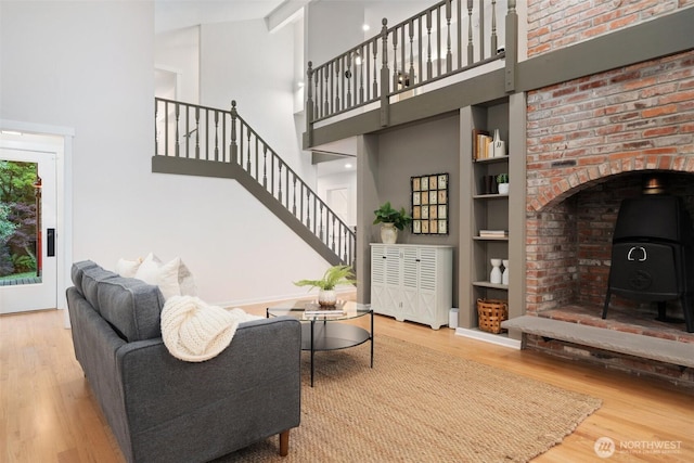 14855 Phelps Rd NE, Bainbridge Island, WA 98110 - living room with a high ceiling, a wood stove, wood finished floors, stairs, and built in shelves