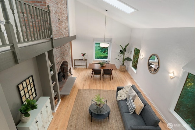 14855 Phelps Rd NE, Bainbridge Island, WA 98110 - living room with high vaulted ceiling, wood finished floors, a fireplace, and a skylight