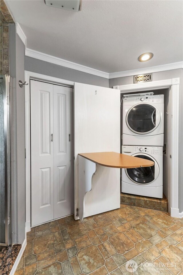 3035 Carbon Ridge St, Enumclaw, WA 98022 - laundry area featuring estacked washer and dryer, ornamental molding, stone finish floors, and recessed lighting